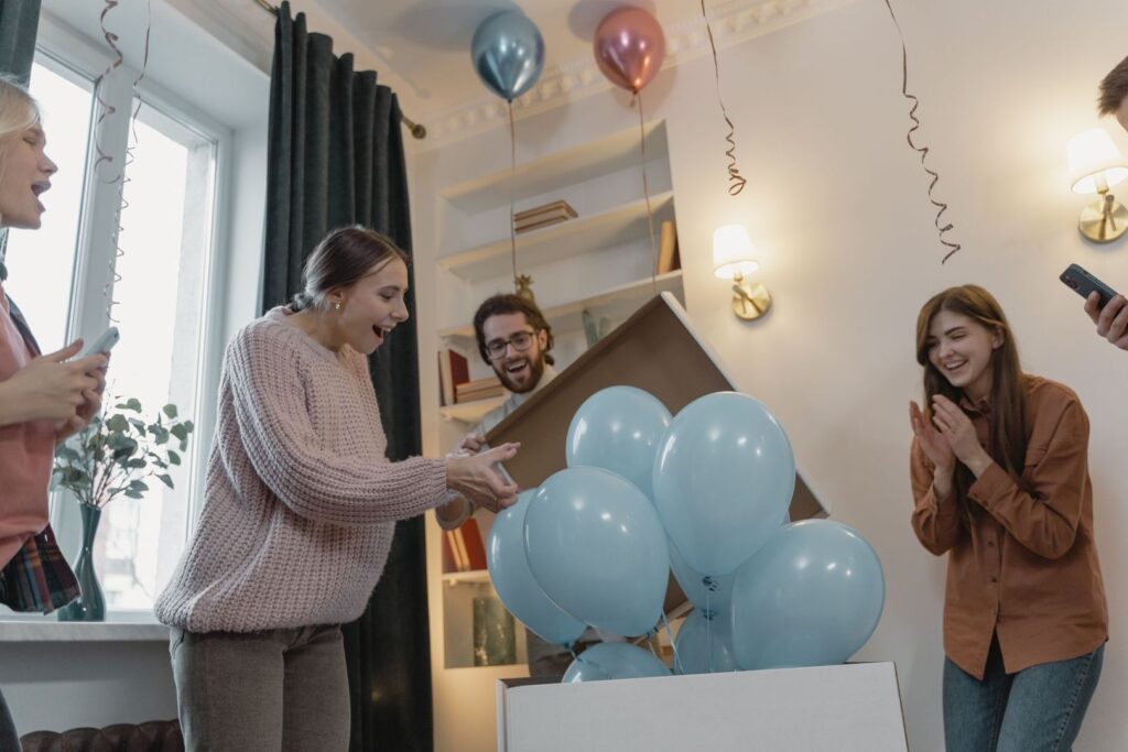 Vänner överraskas av blå ballonger vid en gender reveal-fest
